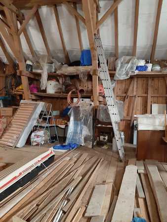 Dachboden mit Holzlatten, Baumaterial, Werkzeugen und einer Leiter in einer Werkstatt.